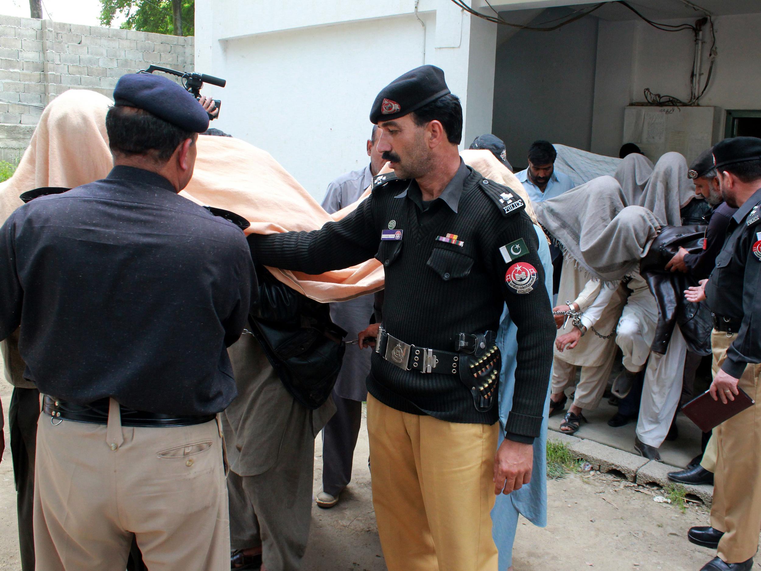 Pakistani police officers escort members of a local tribal council, who have been arrested for burning a girl alive, outside a court in Abbottabad, Pakistan, on Thursday