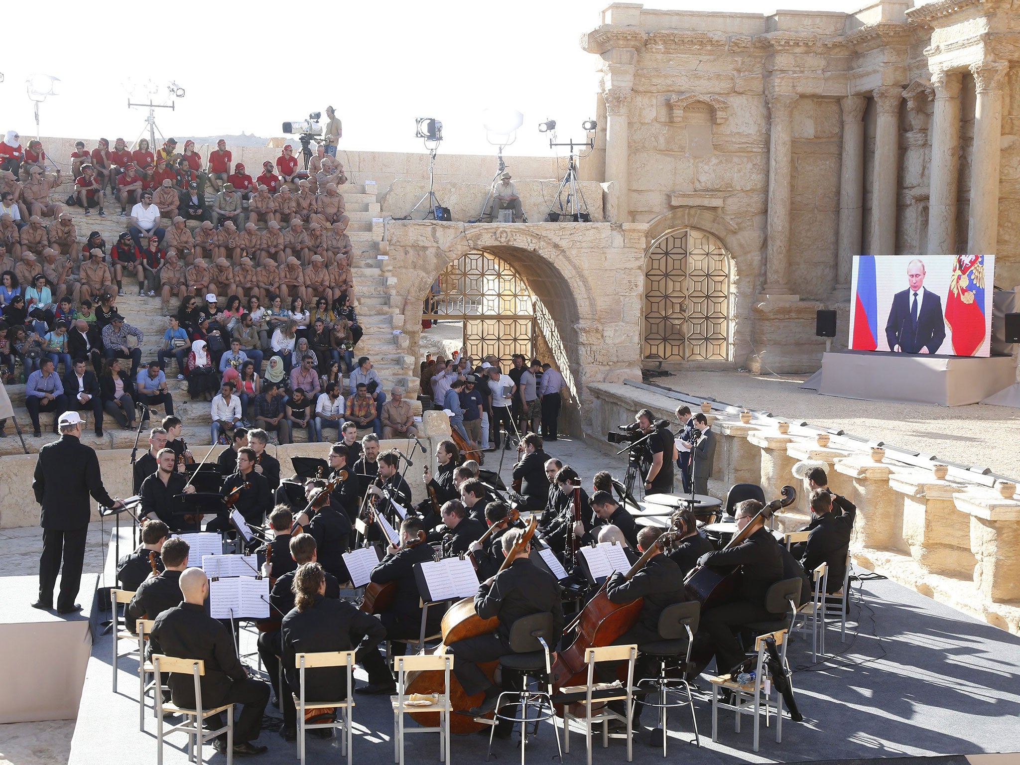 Vladimir Putin delivers a speech via live video feed during a concert by the Mariinsky Symphony Orchestra in Palmyra , Syria, 5 May 2016
