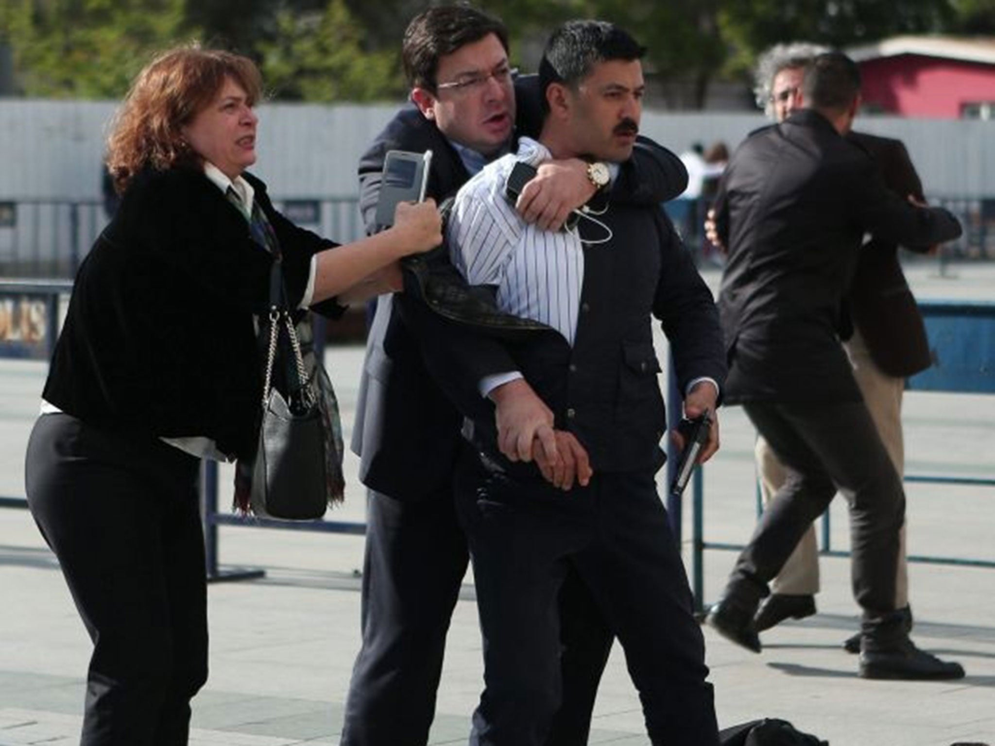 A handout picture provided by Cumhuriyet newspaper shows Dilek Dundar (L), wife of Can Dundar, and opposition party CHP lawmaker Muharrem Erkek try to capture Murat Sahin (R) he attempted to attack Can Dundar in front of the Courthouse in Istanbul, Turkey, 6 May, 2016