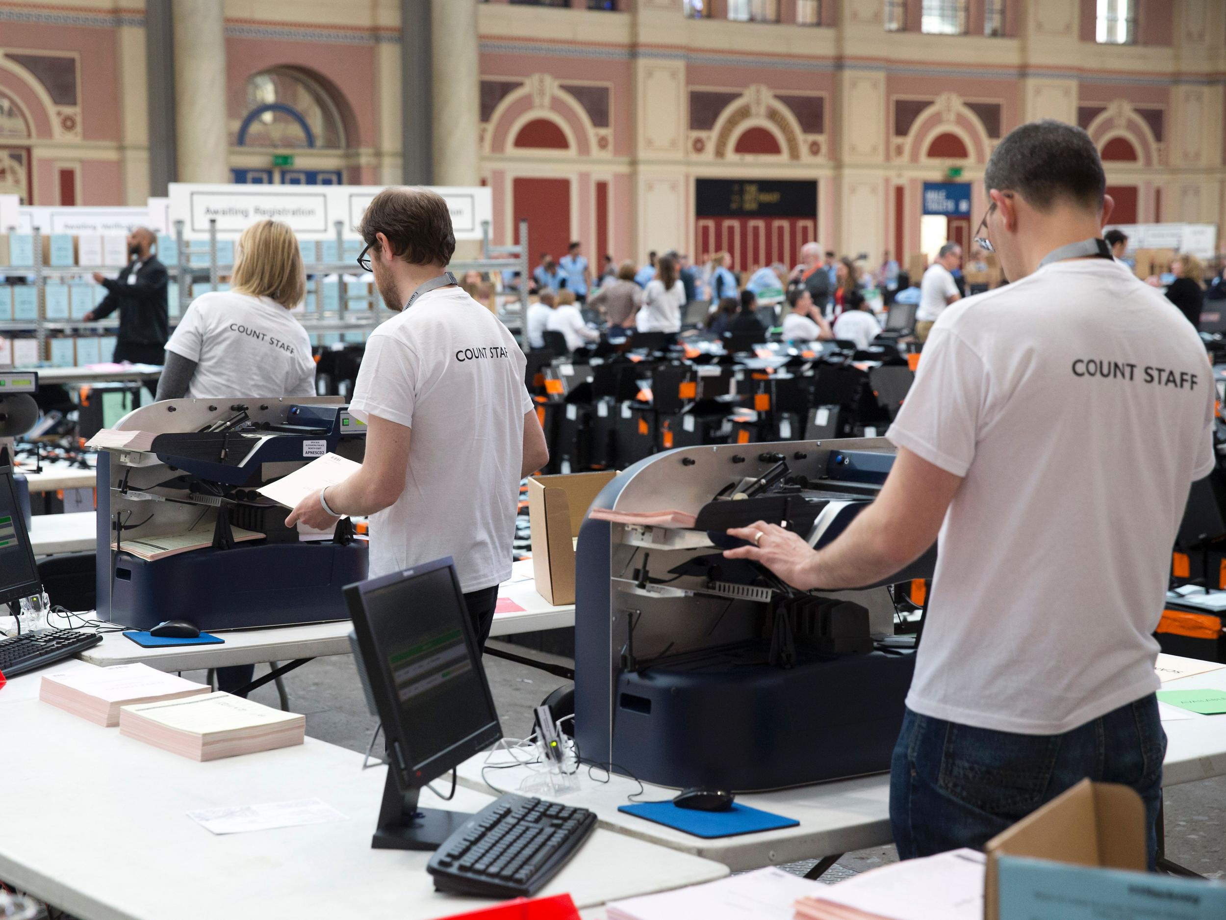 Members of the counting staff use electronic machines to count ballot papers at a count centre in north London on May 6, 2016