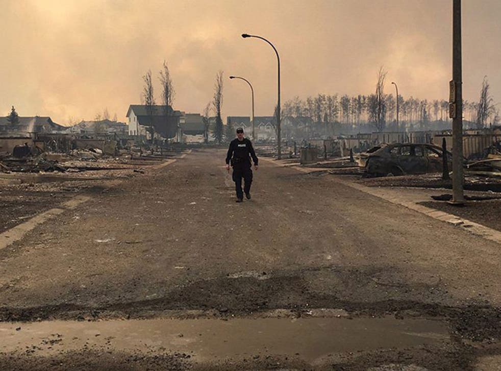 A Canadian police officer surveys the damage on a street in fire-ravaged Fort McMurray, Alberta.