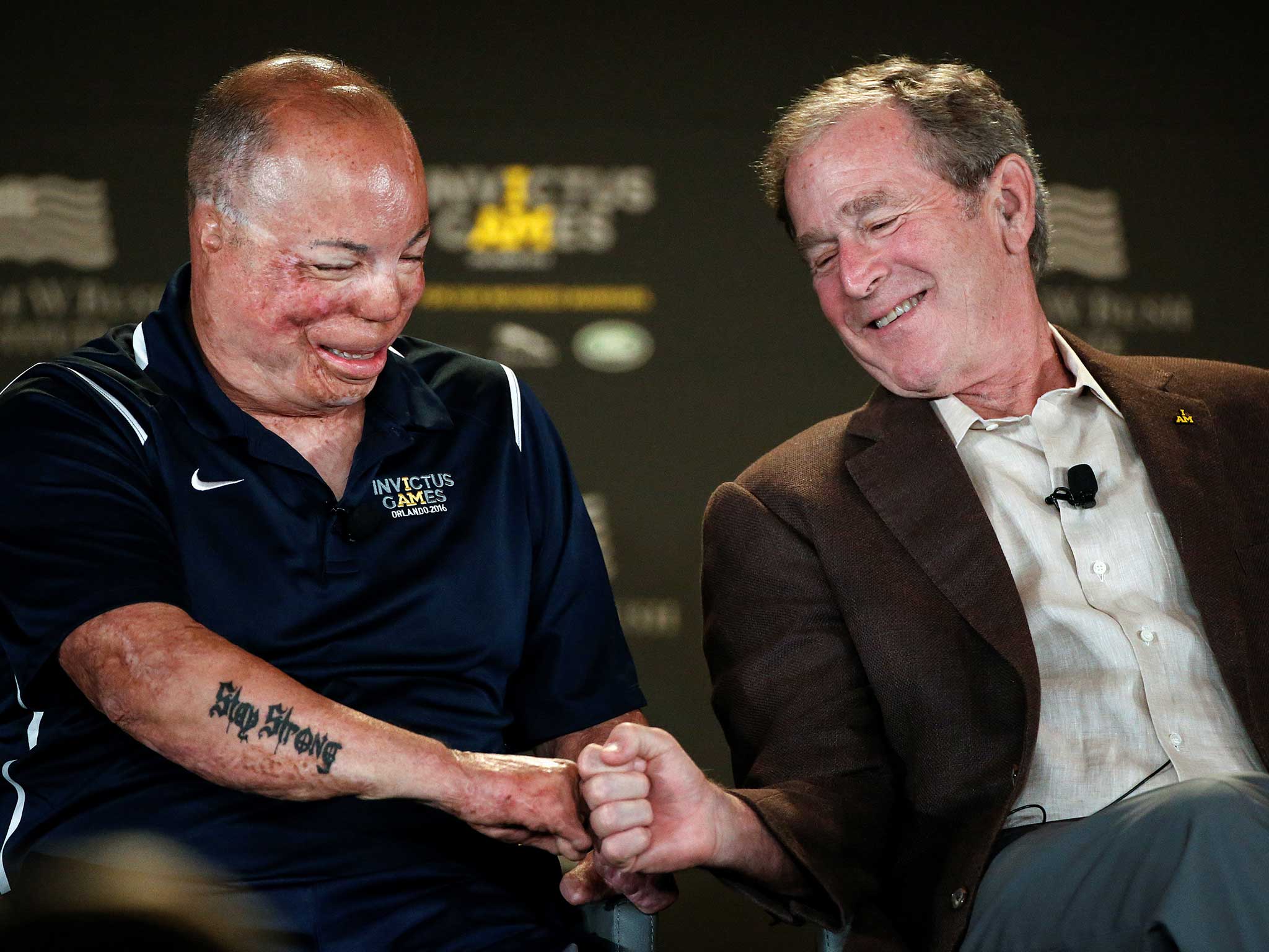 Former U.S. President George W. Bush fist bumps wounded warrior Master Sergeant Israel Del Toro Jr on stage during the Symposium on Invisible Wounds at the Invictus Games in Orlando