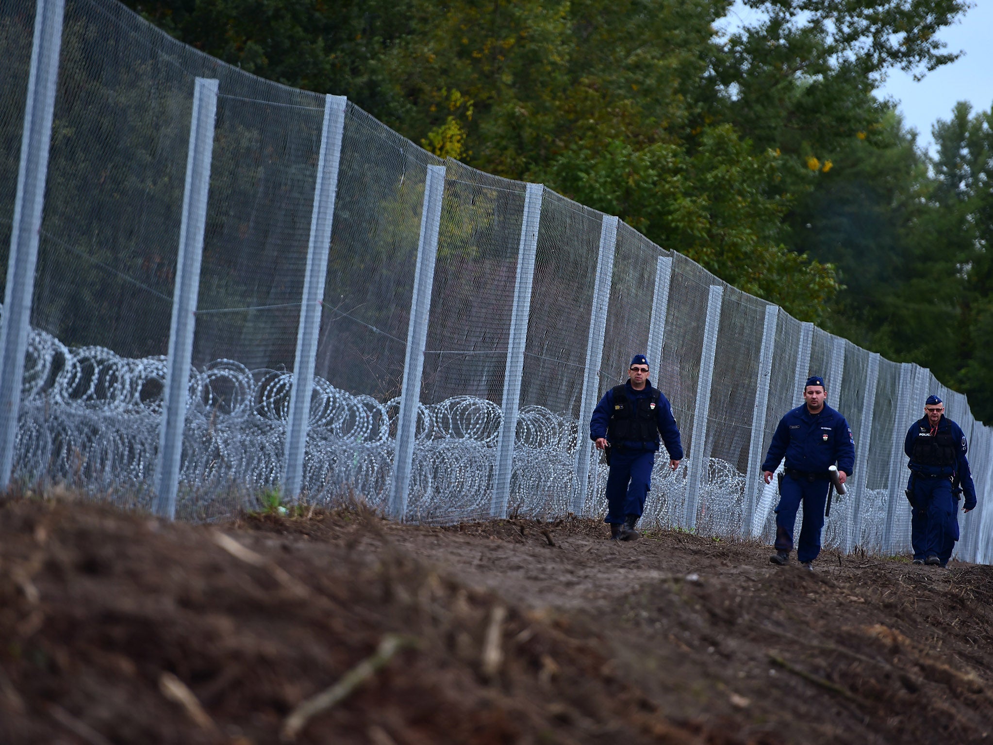 Police officers patrol along a new border fence at the Hungarian border