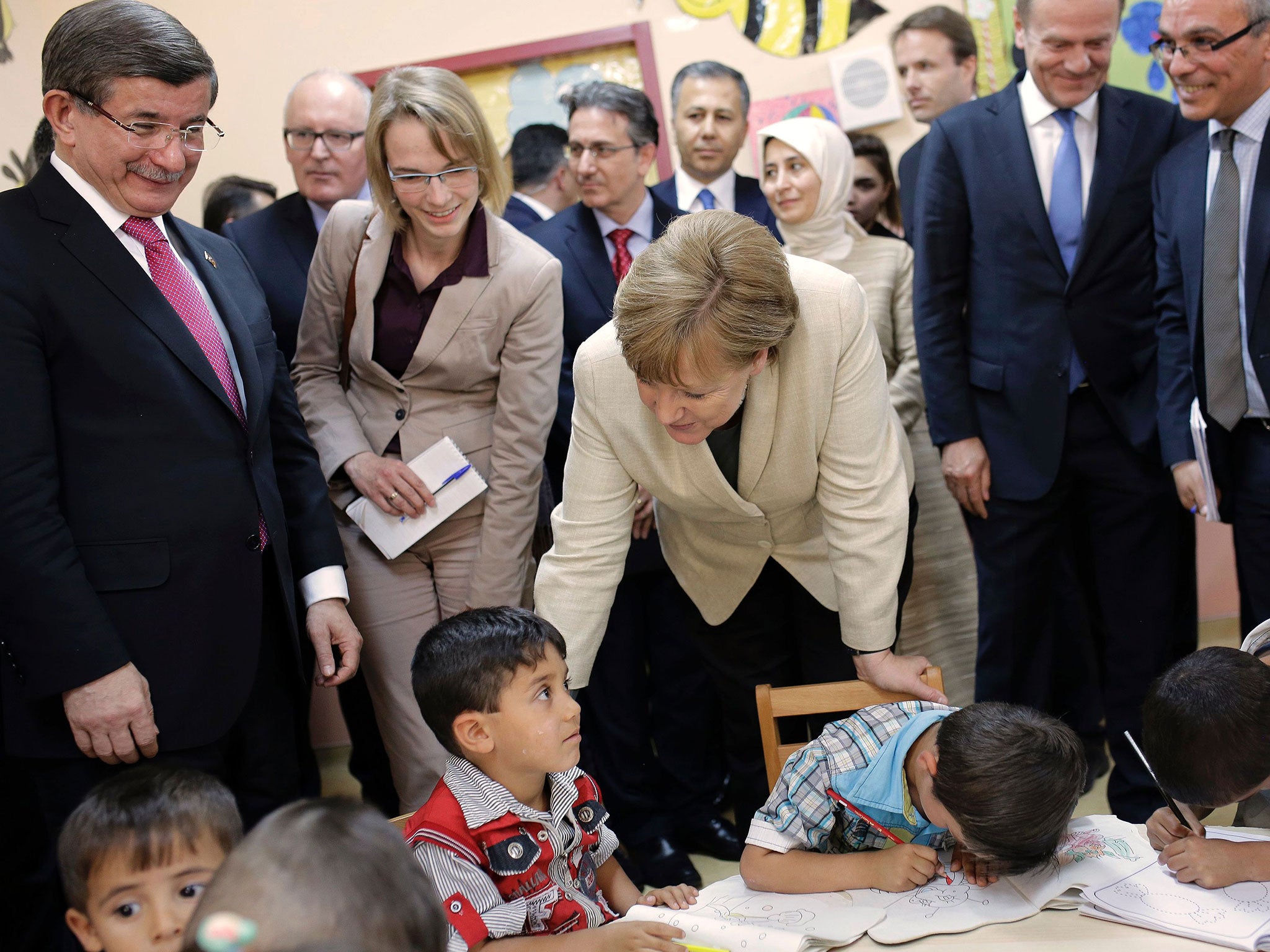 German Chancellor Angela Merkel (centre) and former Turkish PM Ahmet Davutoglu (left) talk with children at a Gaziantep refugee camp