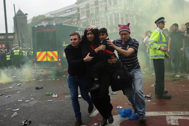 A woman and a child are helped past West Ham fans as people become violent and start throwing bottles at police outside the Boleyn Ground