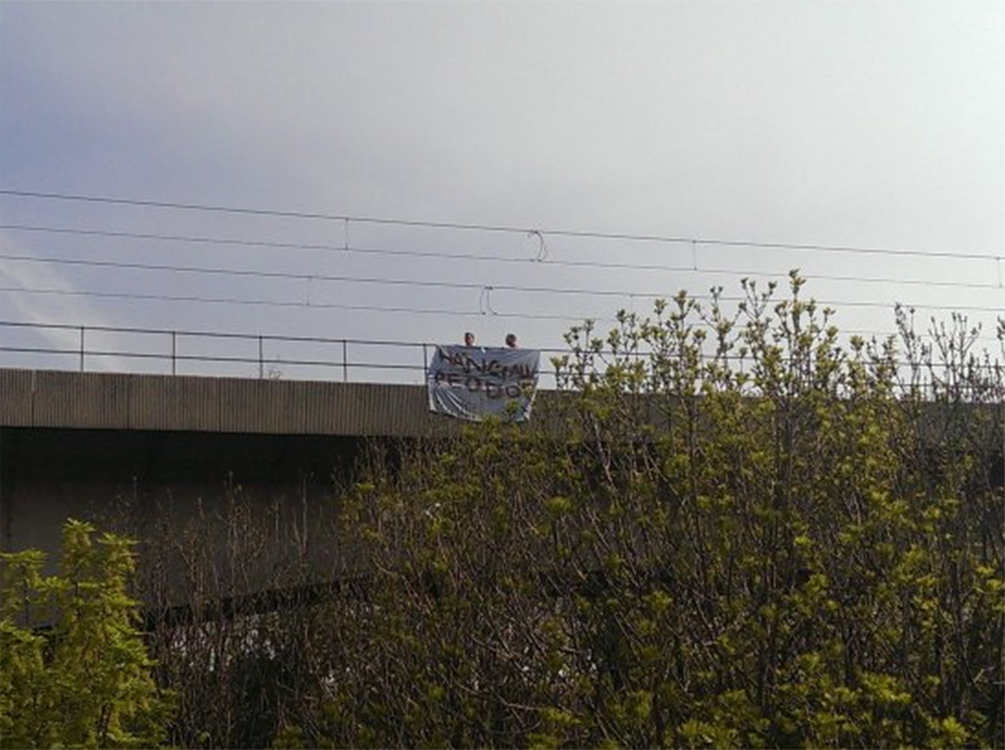 The two men standing with their banner on the Byker viaduct in Newcastle while being watched by police officers