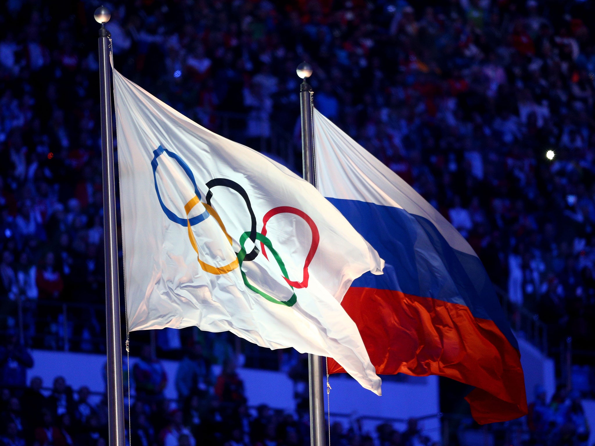 The Olympic and Russian flags flying at the closing ceremony of the 2014 Sochi Winter Olympics