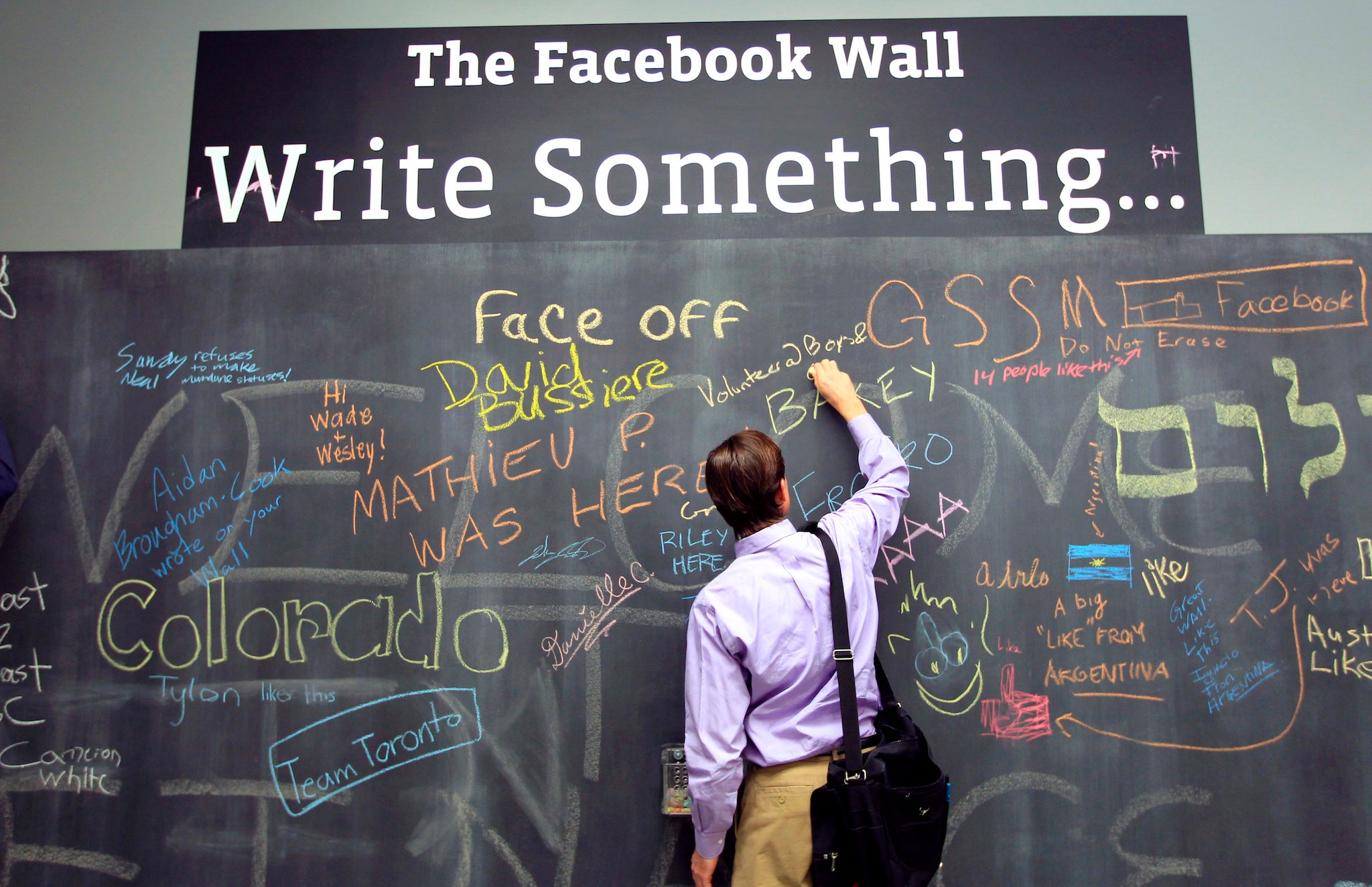 An employee writes a note on the message board at the new headquarters of Facebook in Menlo Park, California January 11, 2012