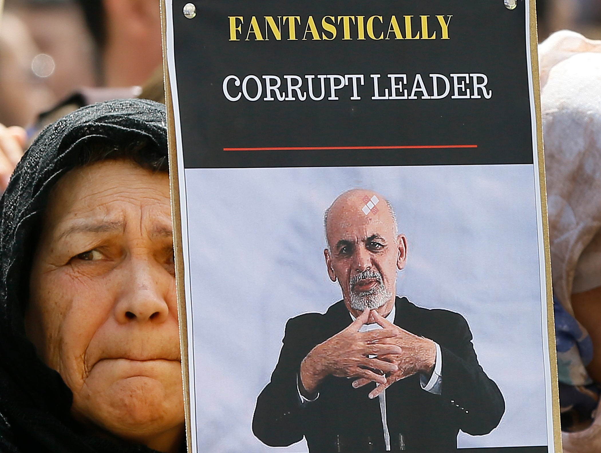 File: A woman holds a banner showing exiled Afghanistan president Ashraf Ghani during a protest outside the Anti-Corruption Summit in London