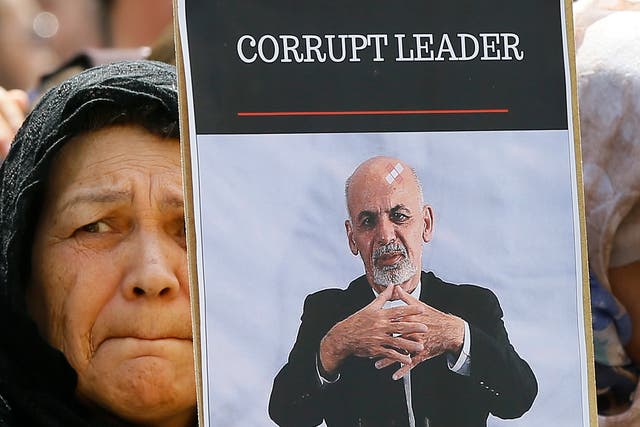 <p>File: A woman holds a banner showing exiled Afghanistan president Ashraf Ghani during a protest outside the Anti-Corruption Summit in London</p>