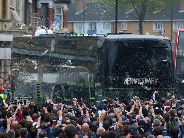 Fans congregate in the street and throw bottles and cans at the Manchester United team bus