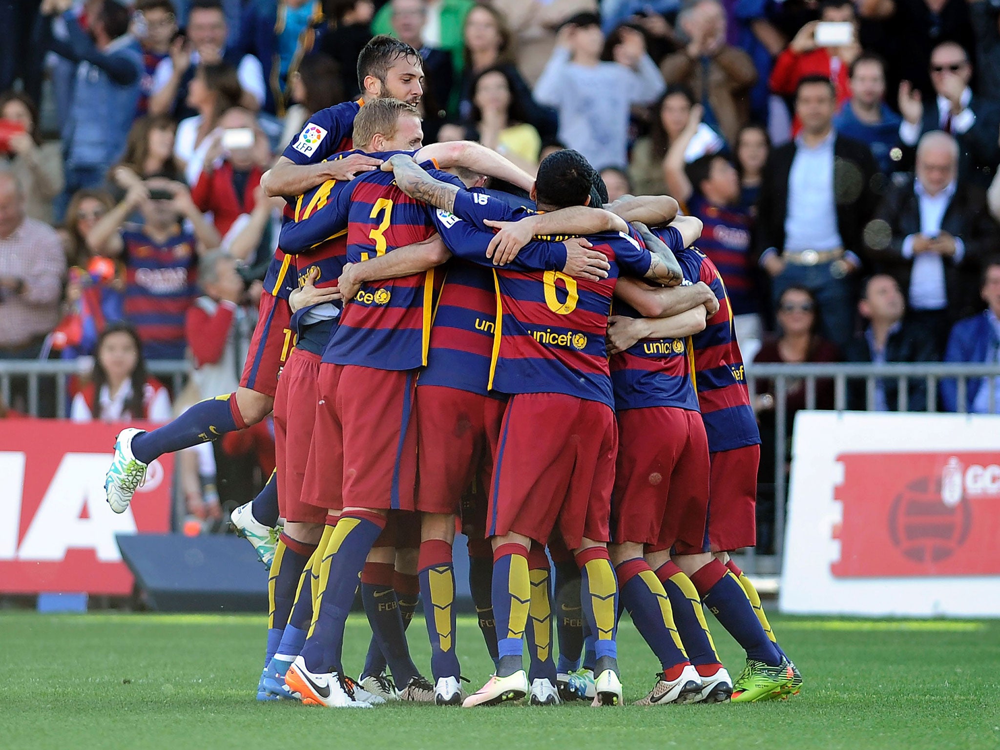 Luis Suarez is mobbed by his team-mates after firing Barcelona to the title