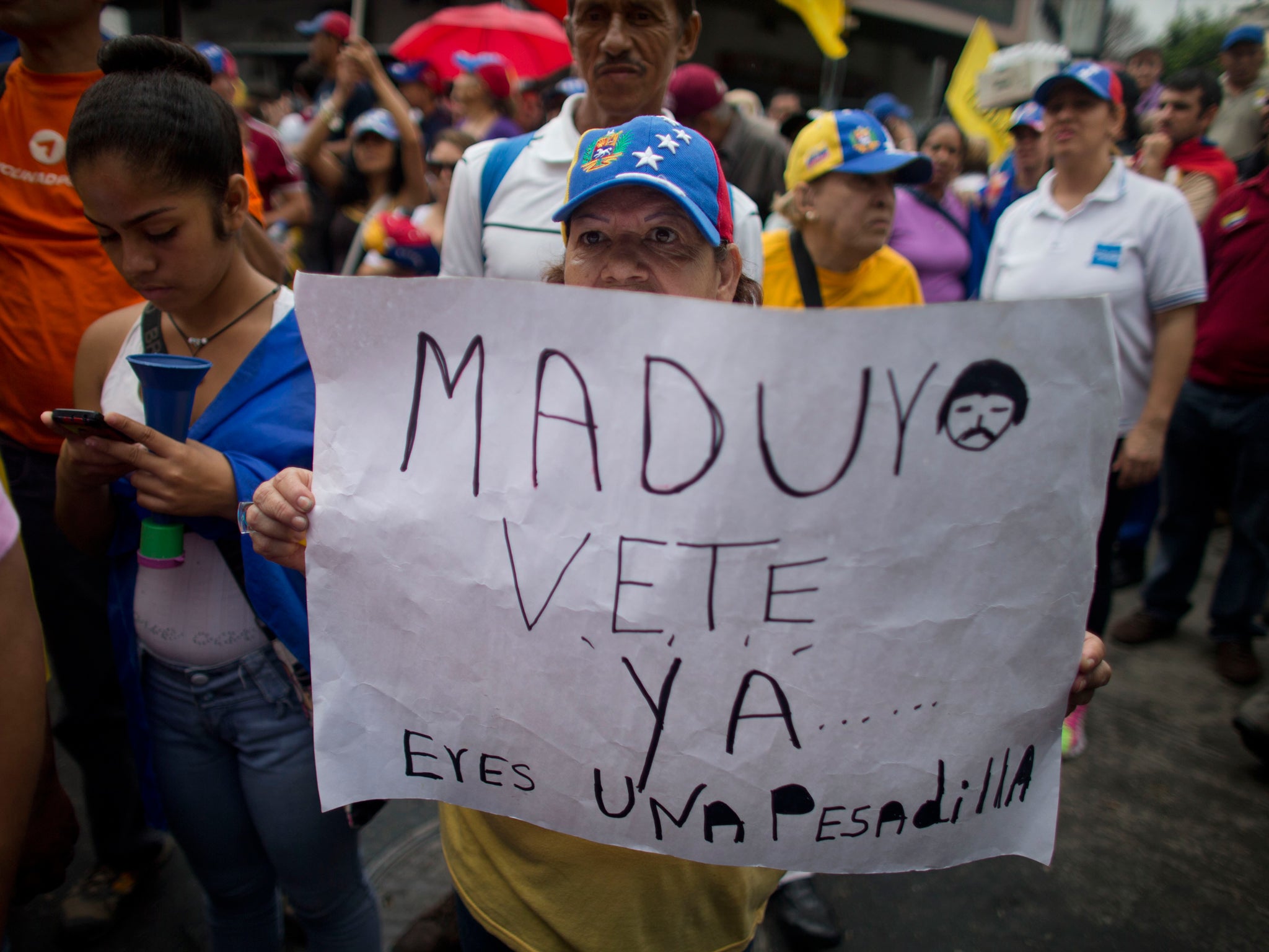 Protestor holds a sign that reads "Maduro leave already......you are a nightmare!" AP