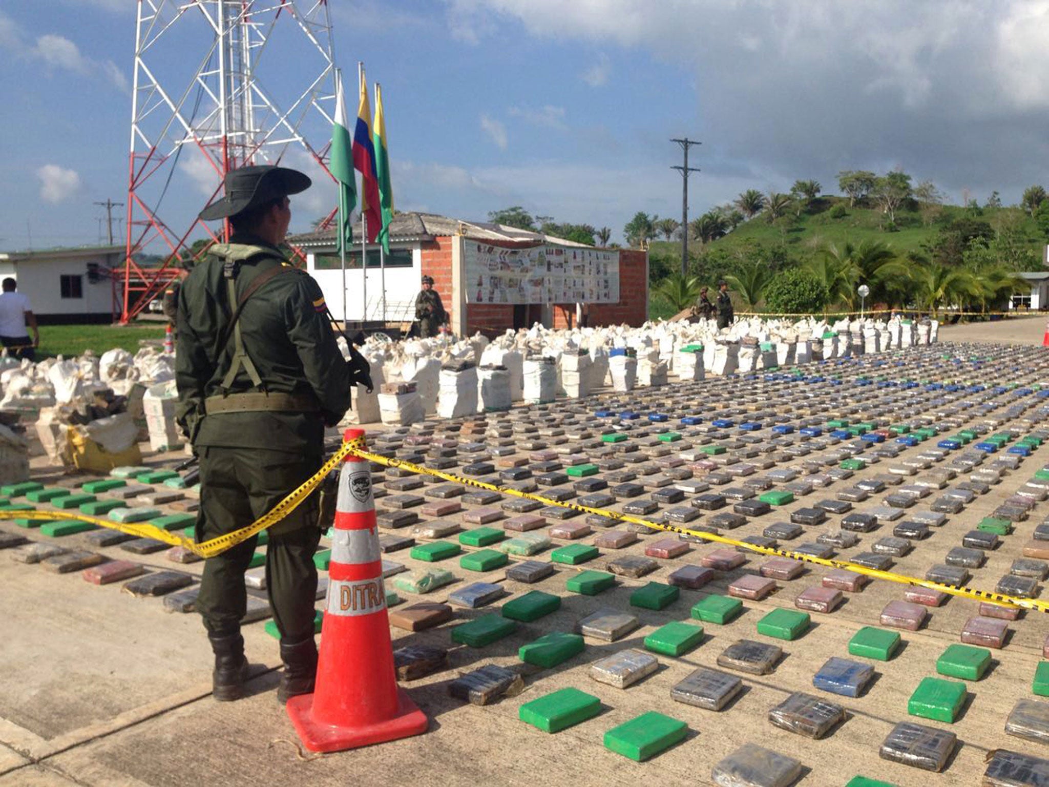 A Colombian national policeman stands guard in front of packages of cocaine, which were confiscated