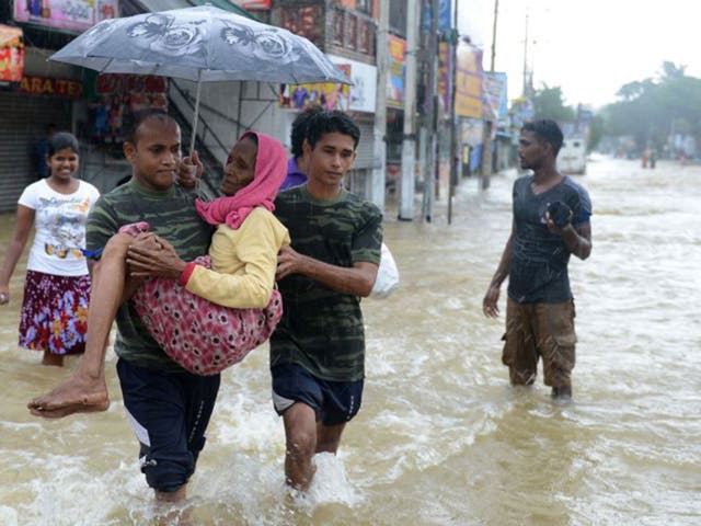 Members of a Sri Lankan Army rescue team carry a woman to safety through floodwaters in the suburb of Kaduwela in capital Colombo