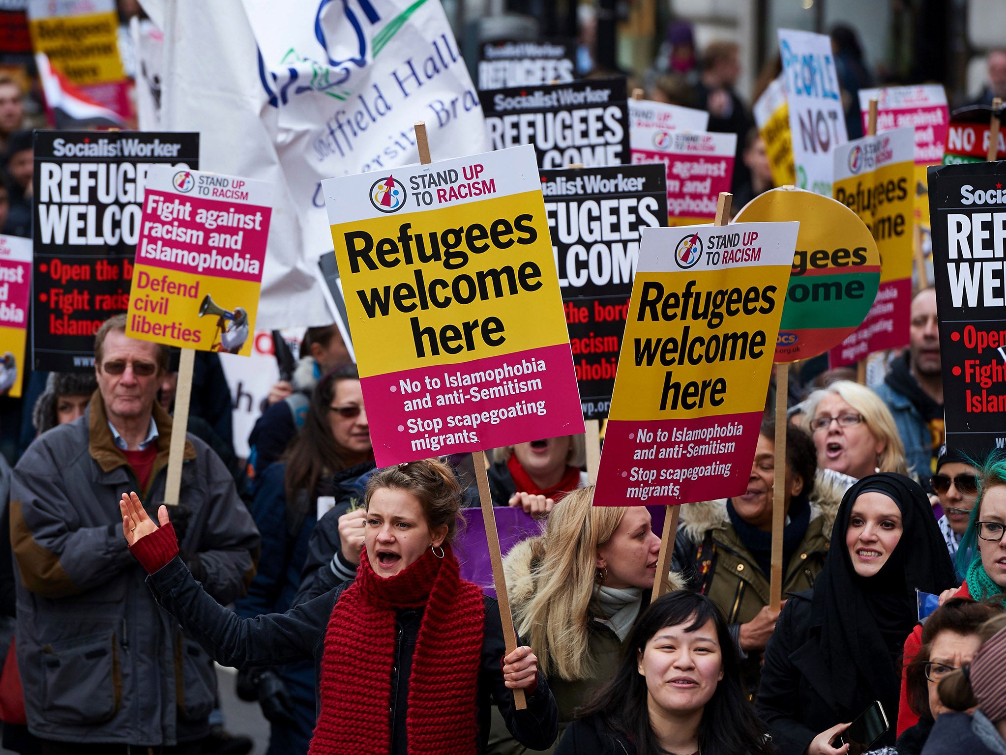 Demonstrators hold banners in support of refugees as they march through central London on March 19