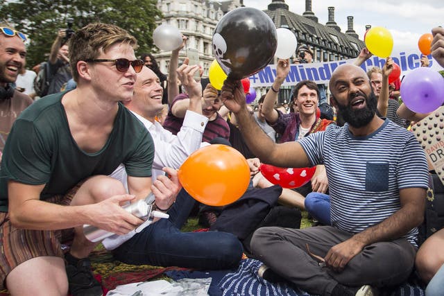 Dozens of protesters stage a mass inhalation of Nitrous Oxide, commonly known as laughing gas, outside the Houses of Parliament on August 1, 2015. The group of demonstrators inhaled the gas from balloons and chanted in protest at the government's proposed Psychoactive Substances Bill.