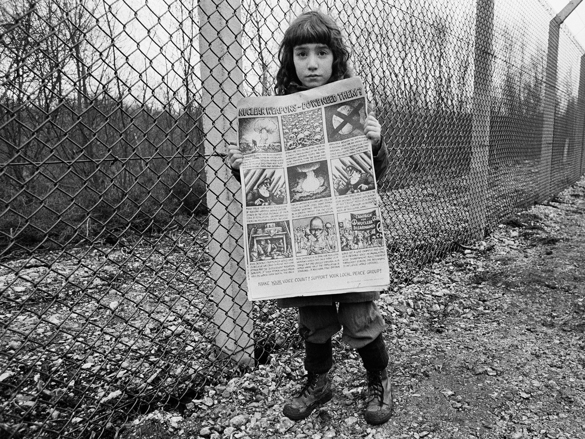 little girl holds anti-nuclear posters in front of the base