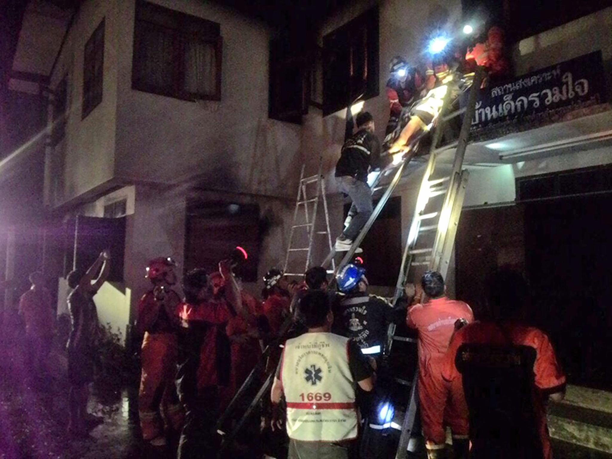 Thai firefighters and rescue workers remove an injured Thai student (top) after a fire broke out at a school dormitory in Chiang Rai province, northern Thailand