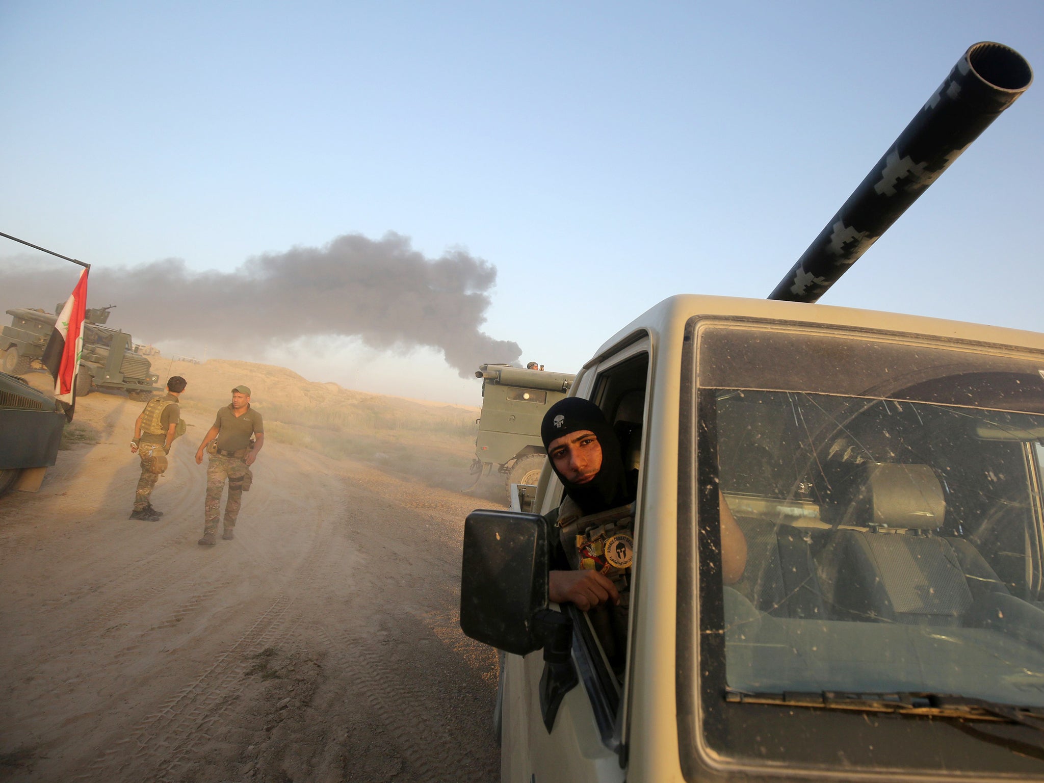 Smoke billows in the background as Iraqi pro-government forces advance towards the city of Fallujah