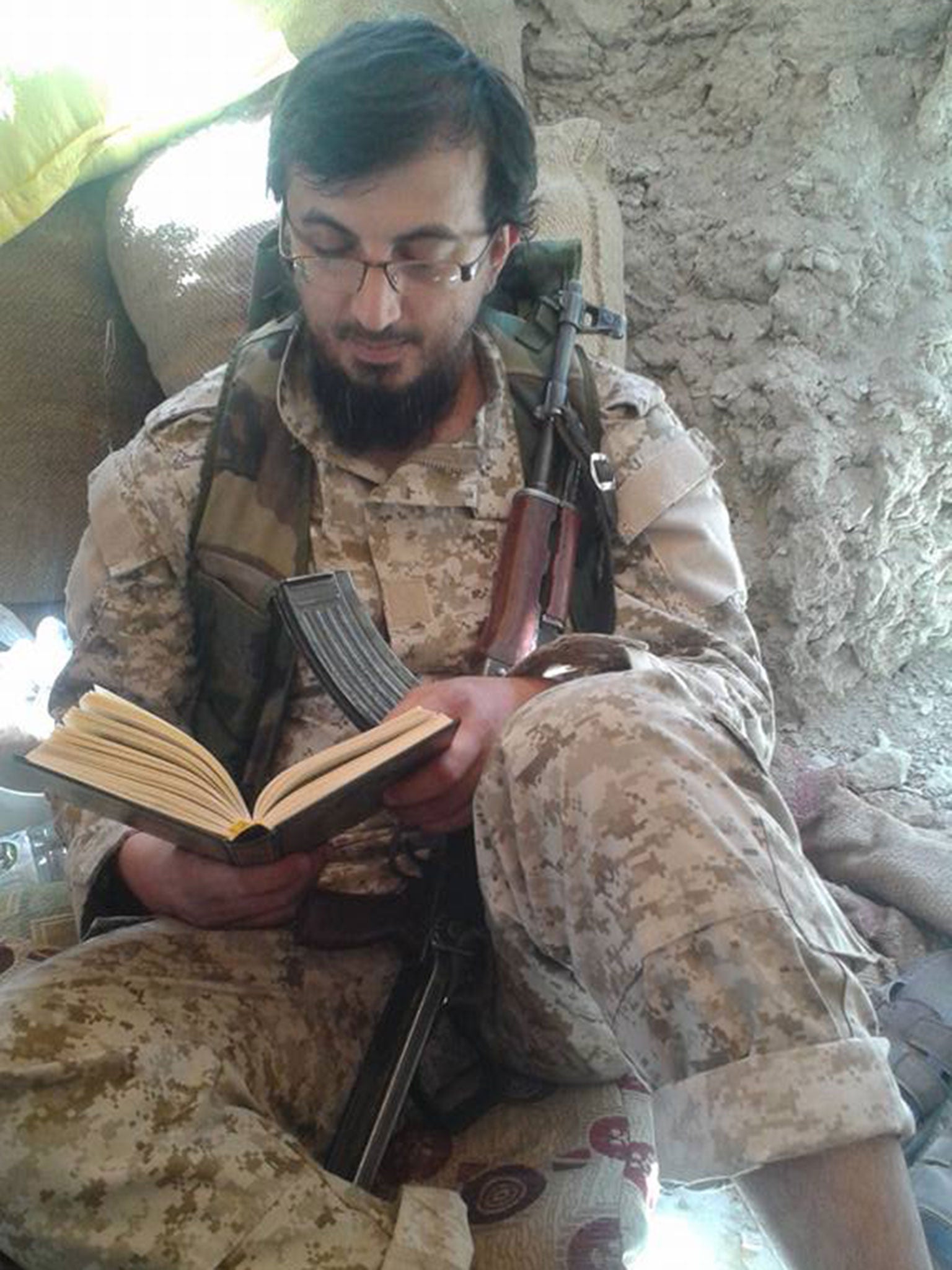 Another image on Issam Abuanza's Facebook page shows him dressed him combat fatigues, reading the Quran with an AK-47 assault rifle resting against his body