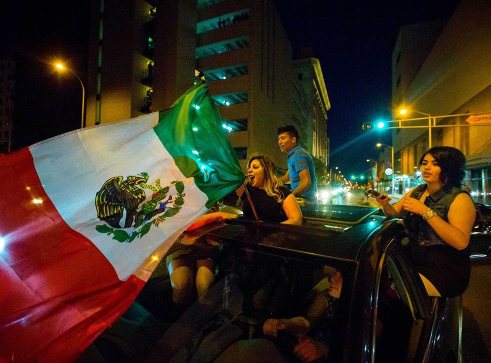 A woman waves the Mexican flag while driving past the Albuquerque Convention Center after a rally by Republican presidential candidate Donald Trump, Tuesday, May 24, 2016