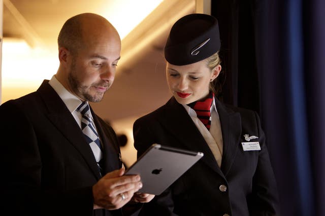 British Airways staff use an iPad to check the passenger list