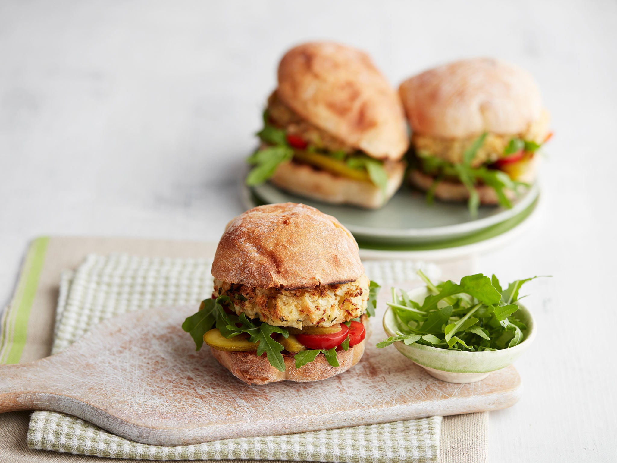 Serve cauliflower burgers in a ciabatta roll with tomatoes, rocket and gherkins