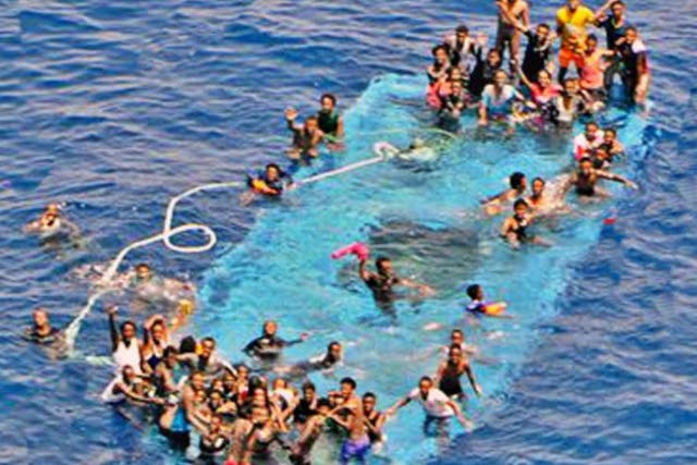 A handout picture released by the European Union Naval Force - Mediterranean (Eunavformed) on 26 May 2016 shows people on their overturned boat in Canal of Sicily off the Libyan coast