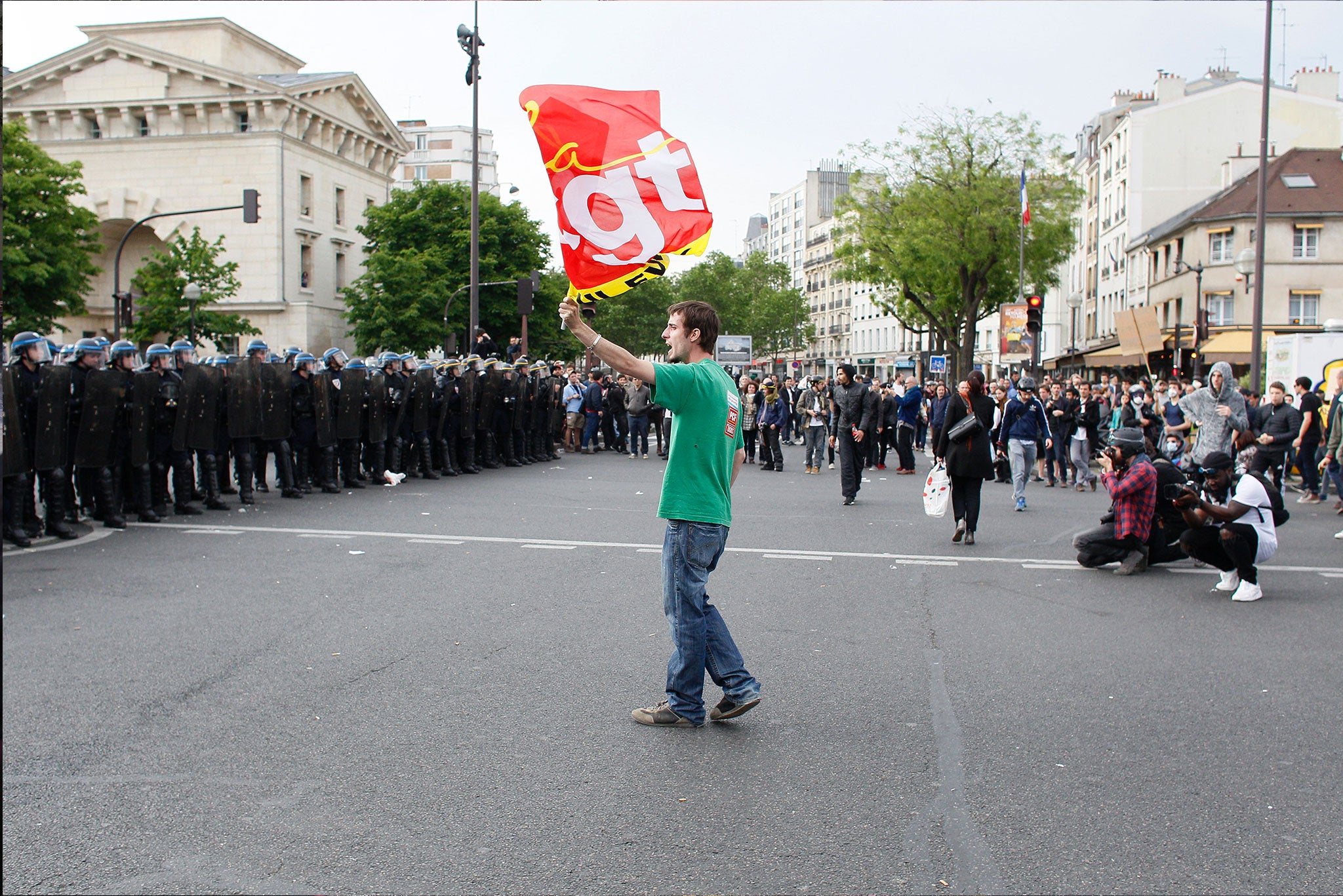 A protester waves a CGT flag at riot police in Paris