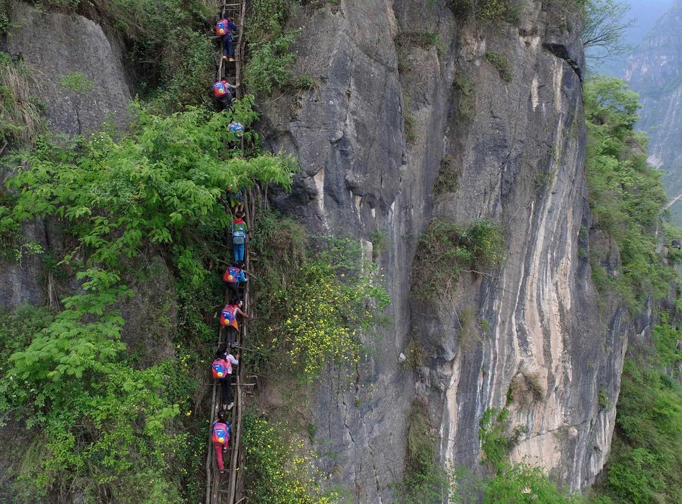 Children carry their school backpacks as they climb a cliff on their way home from school in Zhaojue county, southwest China's Sichuan province