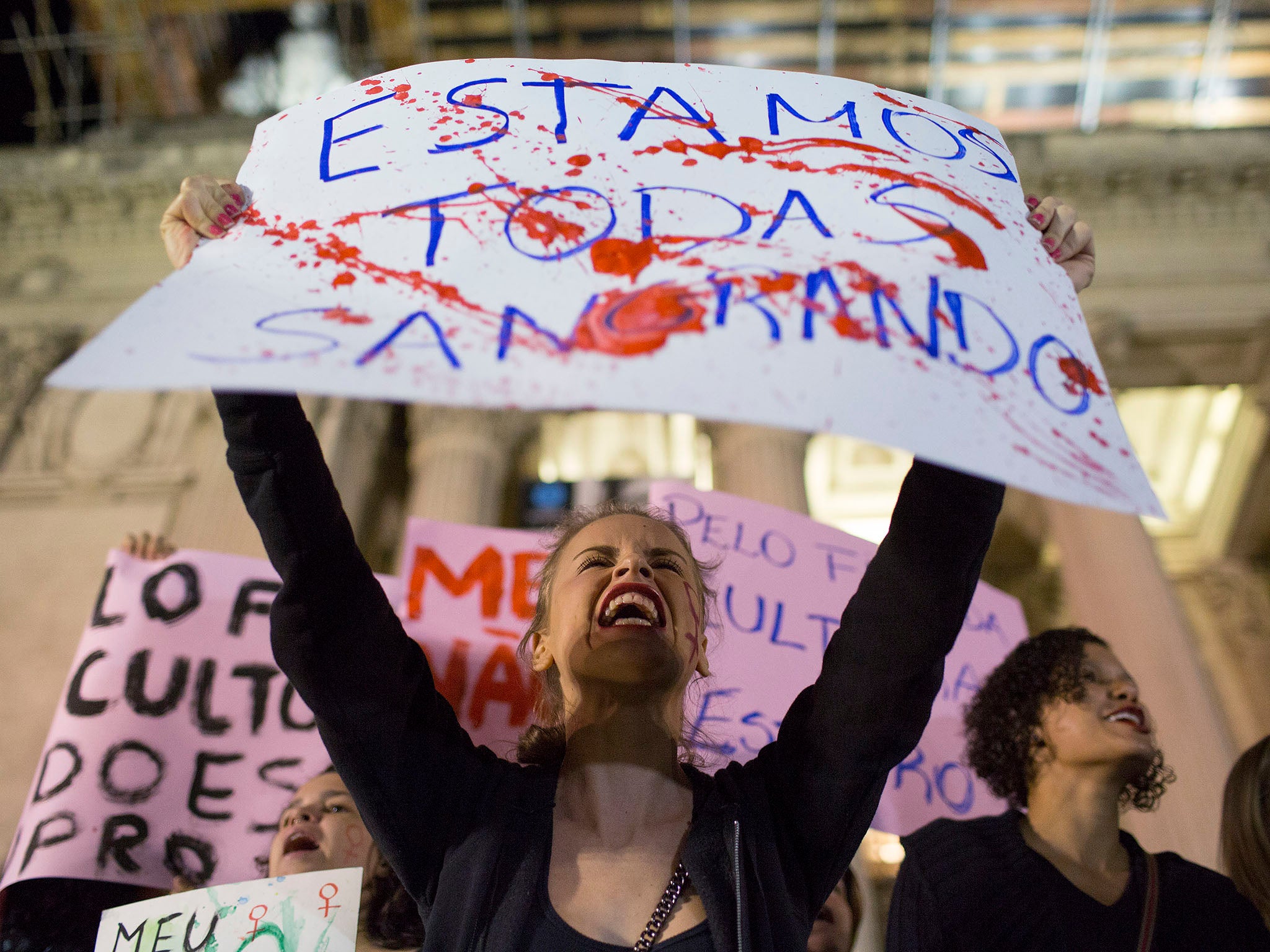 A protester in Rio de Janeiro holding a banner that reads: "We're all bleeding"