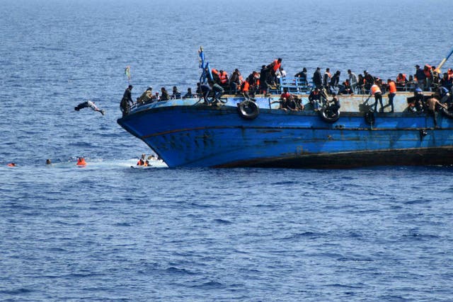 People jump out of a boat before it overturns off the Libyan coast