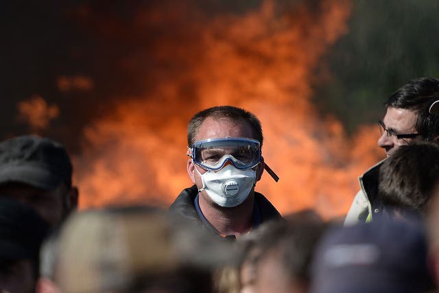 A man with a mask is pictured as workers on strike are evacuated by riot policemen as they block the access to an oil depot near the Total refinery of Donges, western france, on May 27, 2016 to protest against the government's planned labour law reforms
