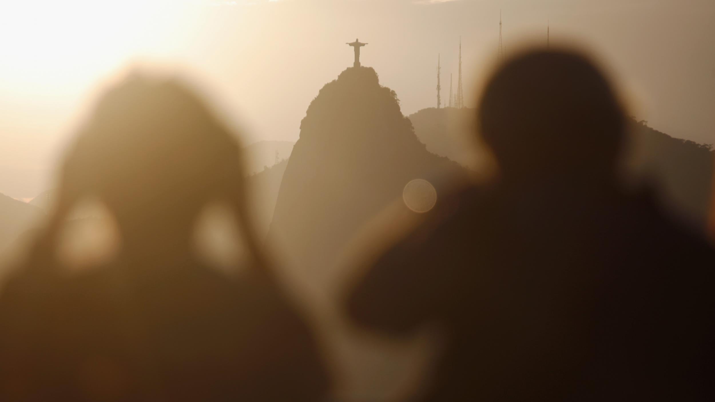 Visitors take photos of the Christ the Redeemer statue from atop the famed Sugar Loaf Mountain, as concerns rise of the impact of the Zika epidemic on Brazil's tourism (Getty)