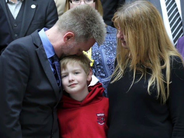 Gregg (L) Kathryn (R) and Lachlan Brain pose for photographers in Scotland's devolved Parliament in Edinburgh, Scotland