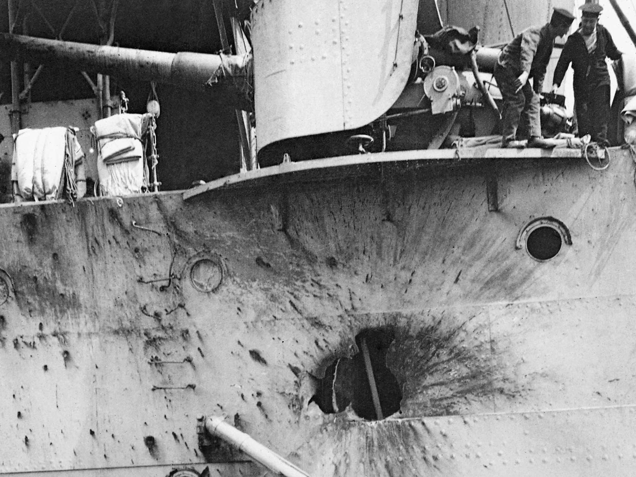 Sailors point to a shell-hole in the side of HMS CHESTER after the Battle of Jutland on 31 May 1916