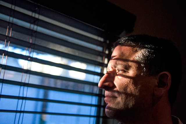 Keith Gartenlaub peers through blinds in the living room of his home in Southern California. Gartenlaub has been charged with possession of child pornography which he claims is a setup to confess to spy charges he has no knowledge of