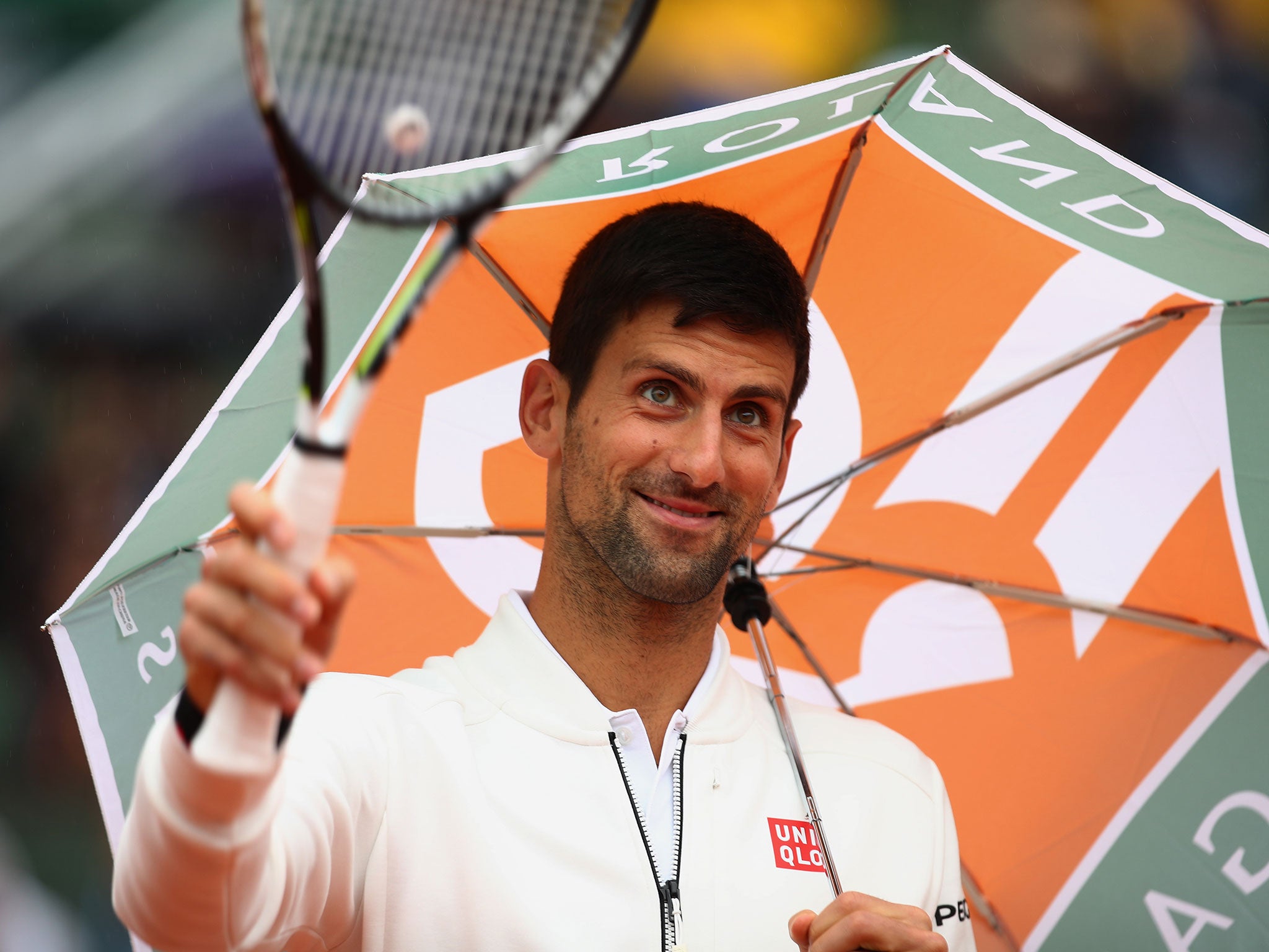 Novak Djokovic shields himself from the rain at the French Open