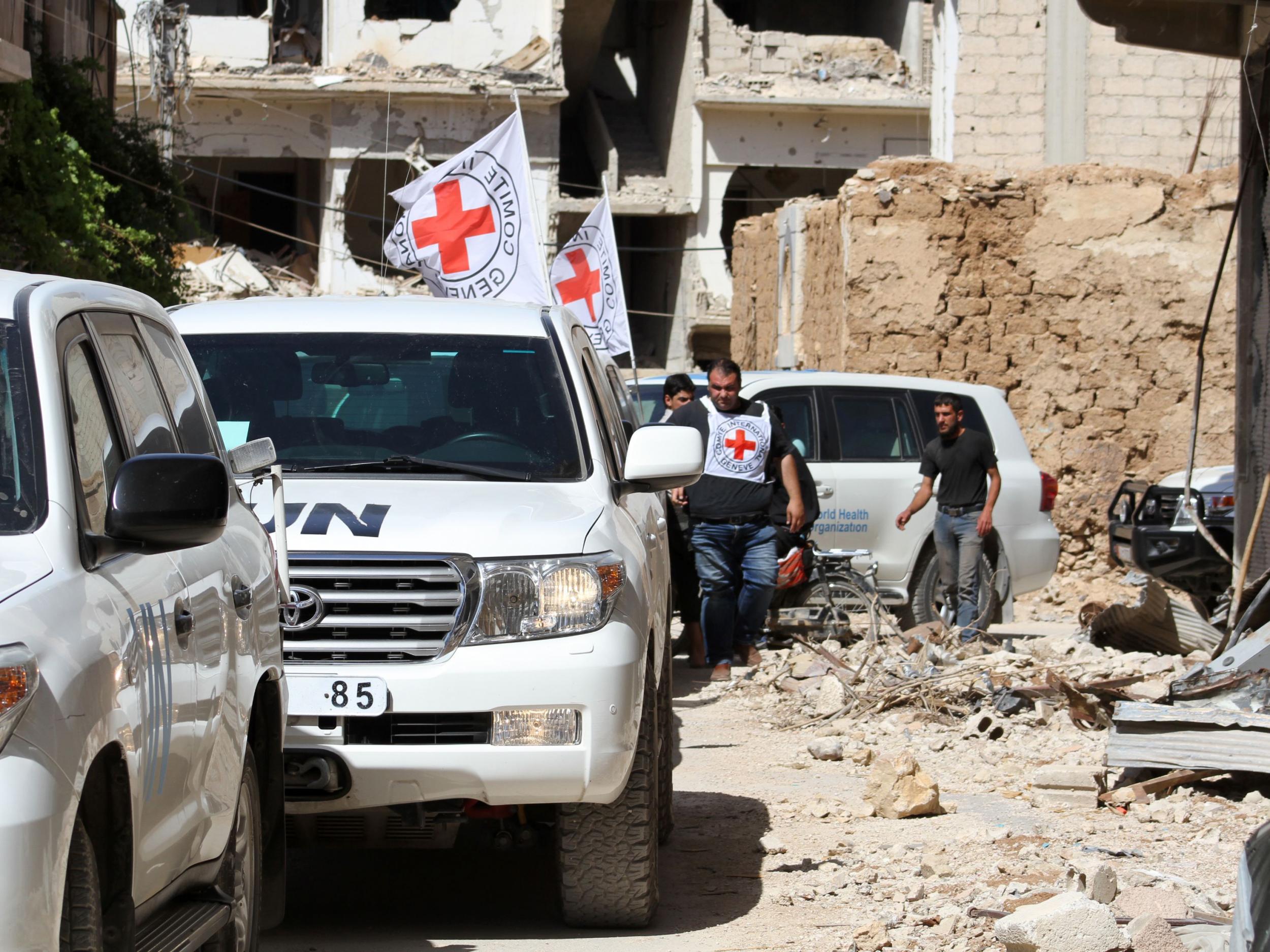 Vehicles of the International Committee of the Red Cross (ICRC) and the United Nations wait on a street after an aid convoy entered the rebel-held Syrian town of Daraya, southwest of the capital Damascus