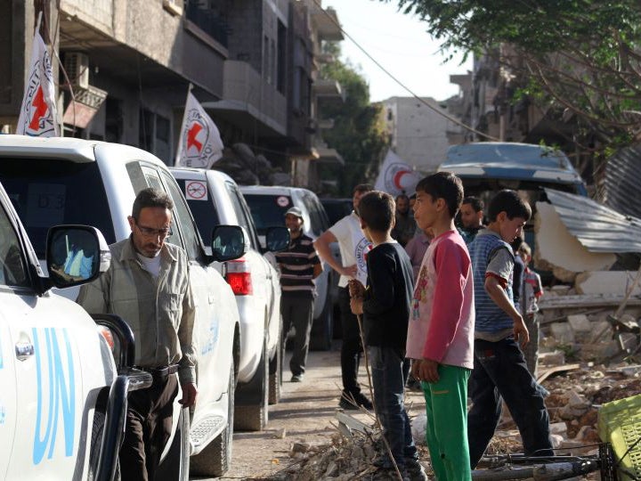 Vehicles of the International Committee of the Red Cross (ICRC), the Syrian Arab Red Crescent and the United Nations wait on a street after an aid convoy entered the rebel-held Syrian town of Daraya, southwest of the capital Damascus