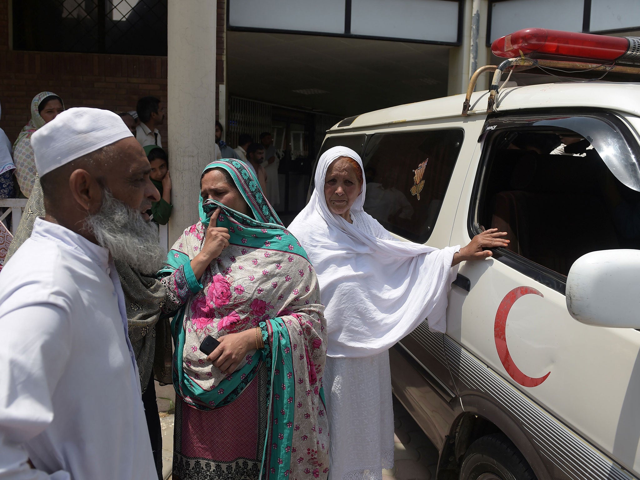&#13;
Relatives stand alongside an ambulance carrying Ms Sadaqat's body &#13;