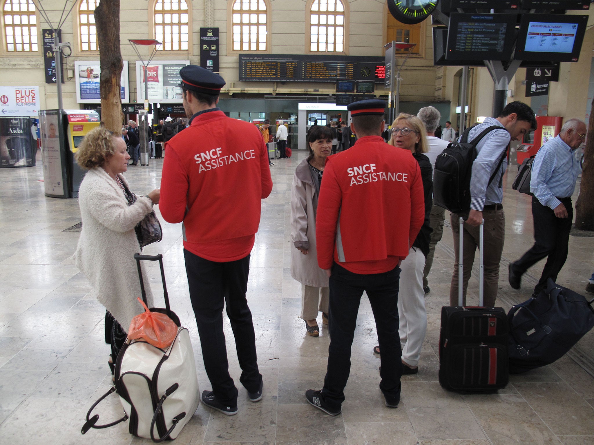 Employees of the state-owned rail operator SNCF help passengers at the Marseille-Saint-Charles railway station in Marseille