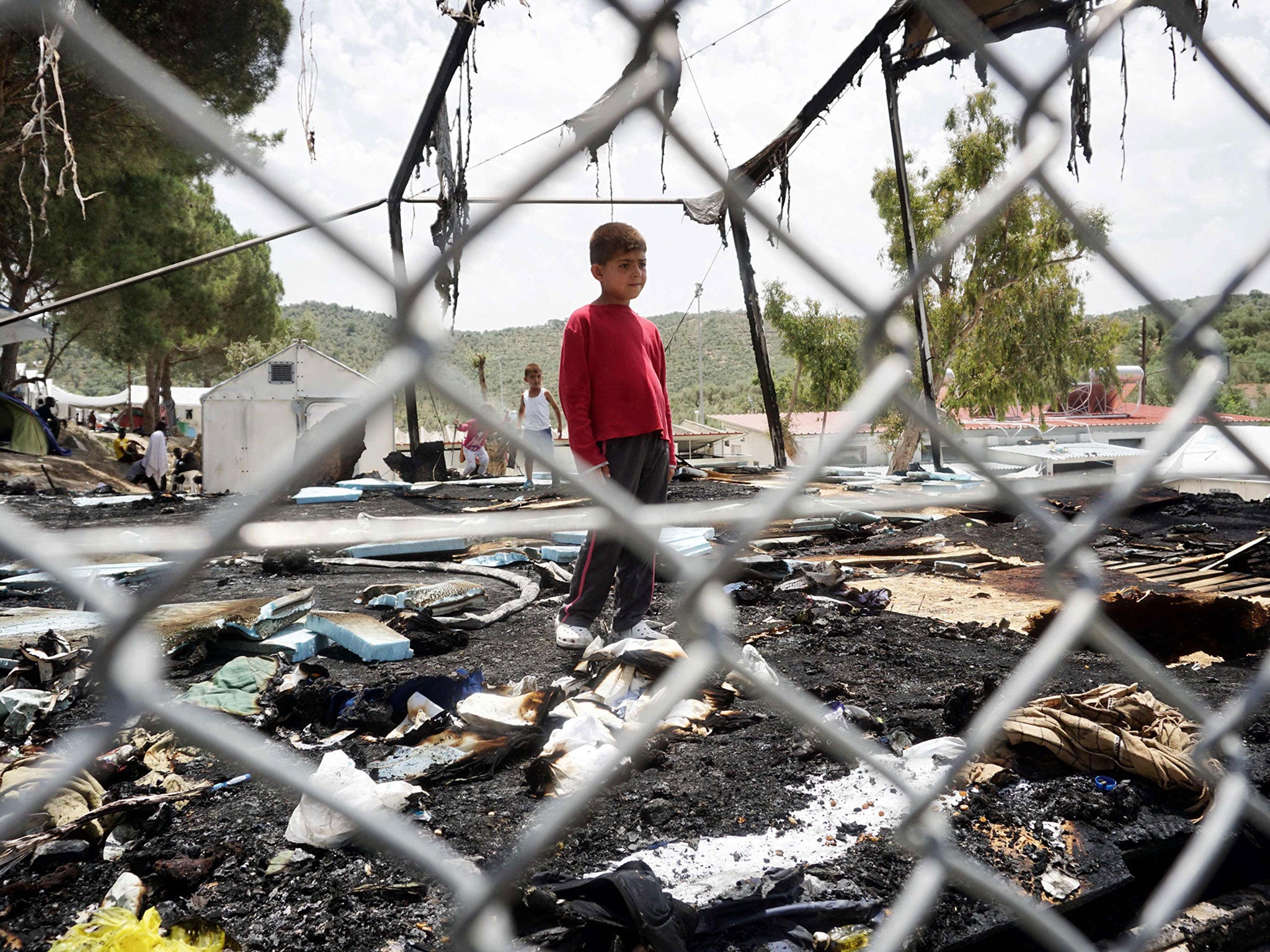 A boy stands among the wreck of a torched tent in the Moria detention camp on the Greek island of Lesbos, on June 2, 2016