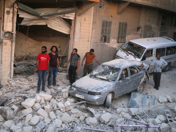 Men inspect damage after an air strike on Aleppo