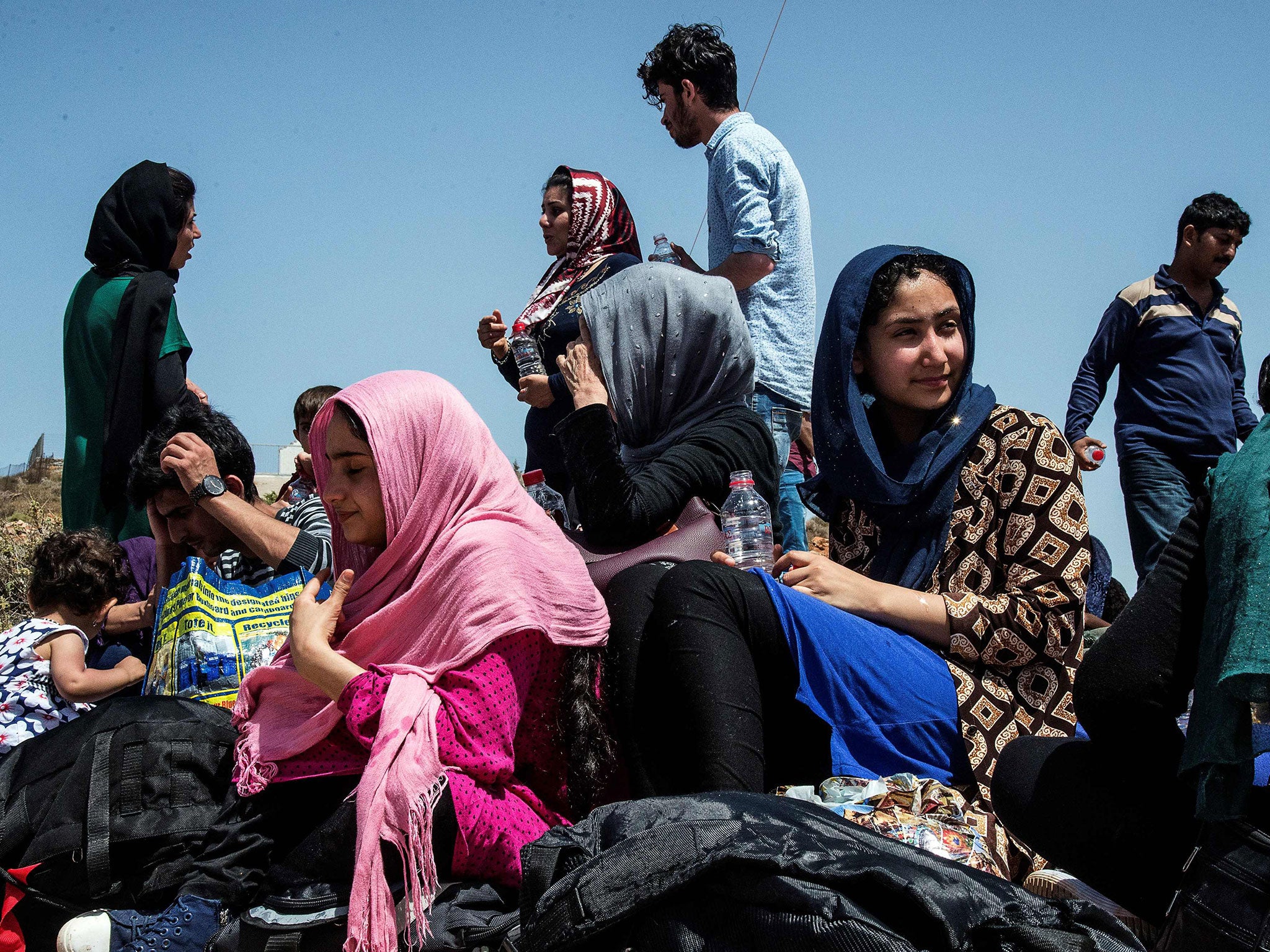 Refugees and migrants sit on the ground upon their arrival by boat a boat on Crete on May 31