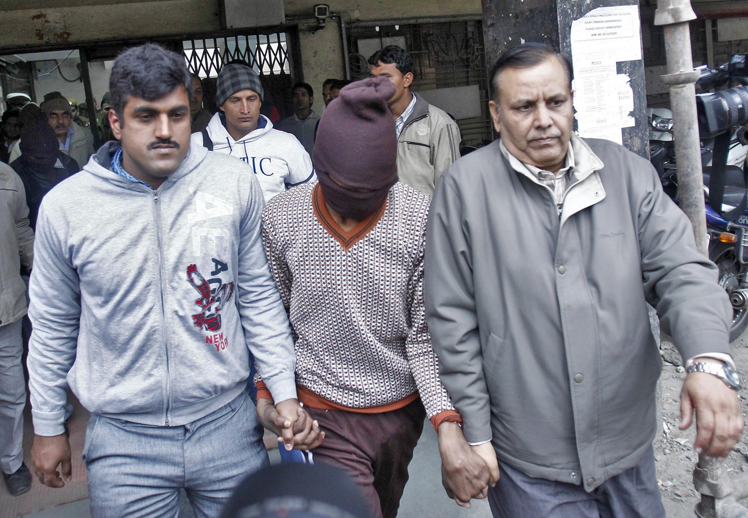 Plain-clothed police escort one of the men (face covered) accused of a gang rape outside a court in New Delhi