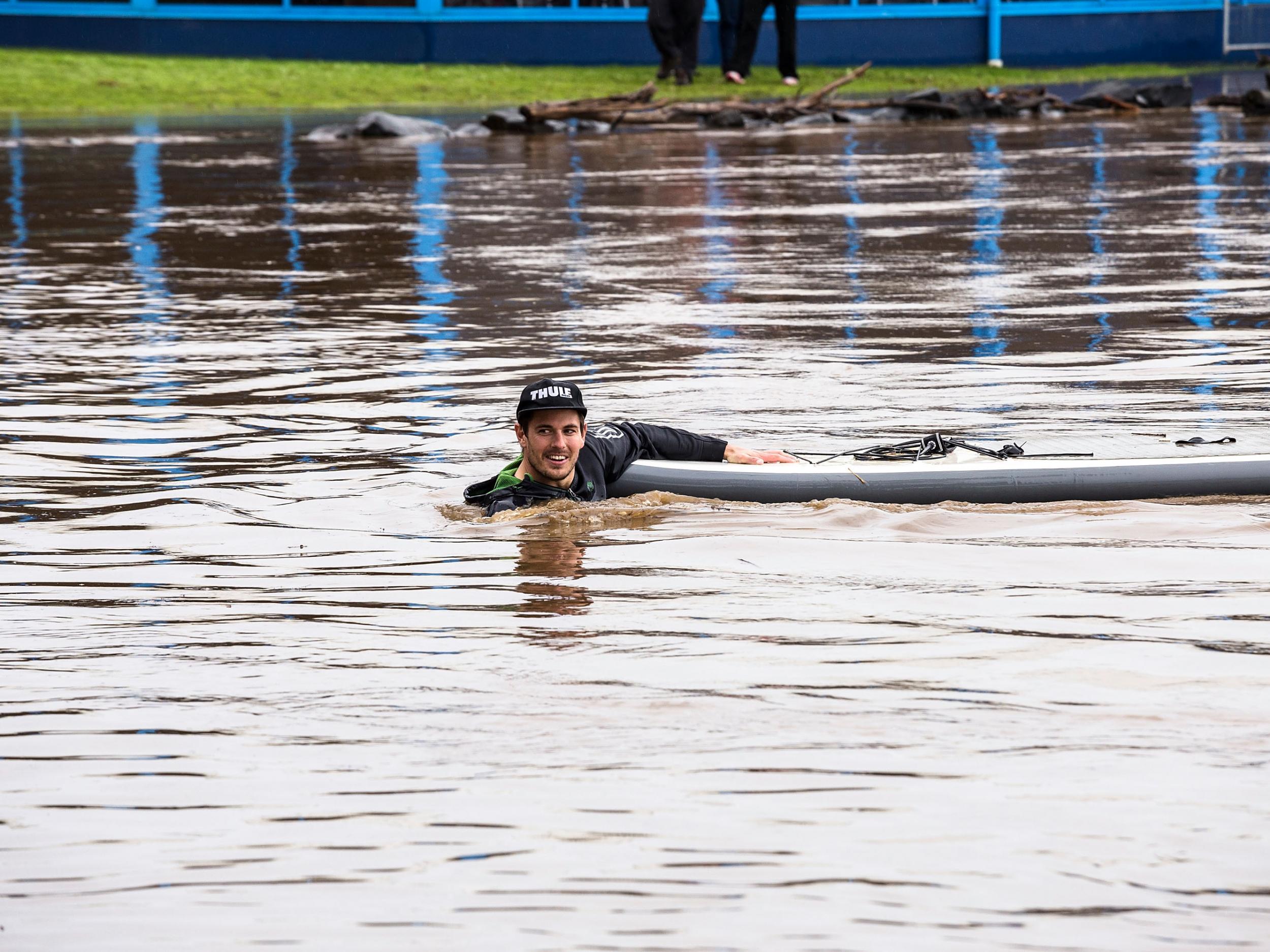 A stand up paddle boarder helps with the rescue of surviving cows and bulls which were washed downstream when the Mersey River (Getty Images )