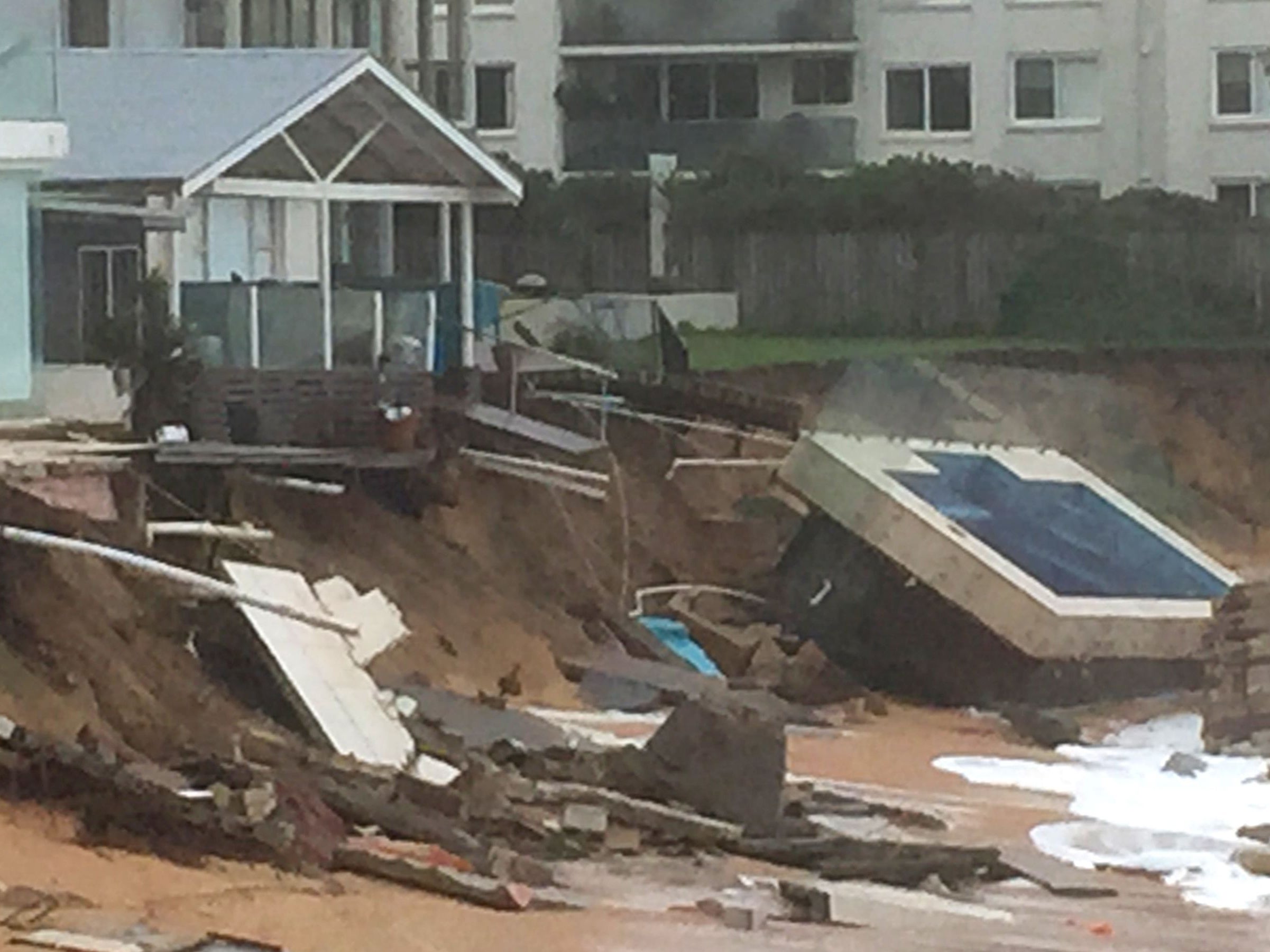 An in-ground pool lies on the beach next to damaged houses after a severe storm at Collaroy on Sydney's northern beaches