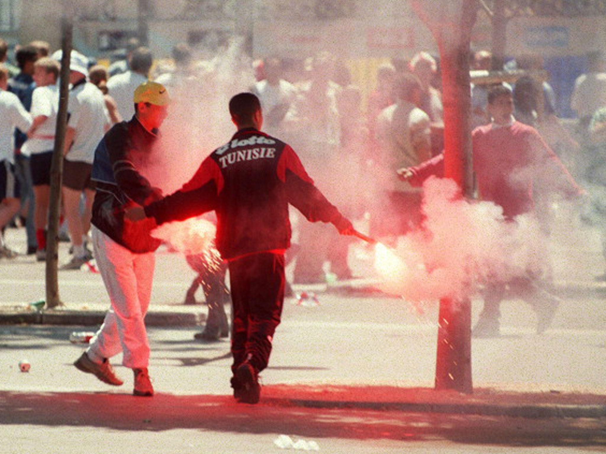 &#13;
Tunisia supporters hold flares during clashes with England fans in Marseilles at the 1998 World Cup finals (Getty)&#13;